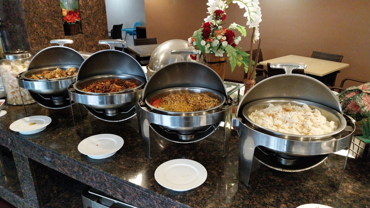 A Filipino buffet line in chafing dishes with rice, noodles and home-style mains ready for serving