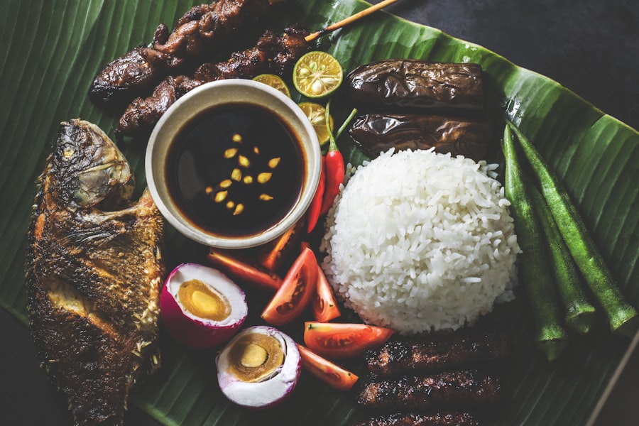 Filipino fiesta platter on banana leaf with grilled fish, pork barbecue, rice and salted egg