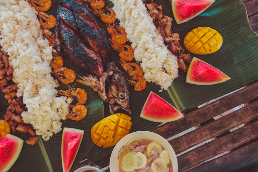 Filipino boodle-style feast with grilled fish, shrimp, rice and fresh fruit on banana leaves